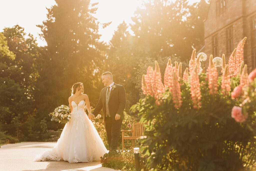 Bride and groom walk in the courtyard of Standon Hall during golden hour