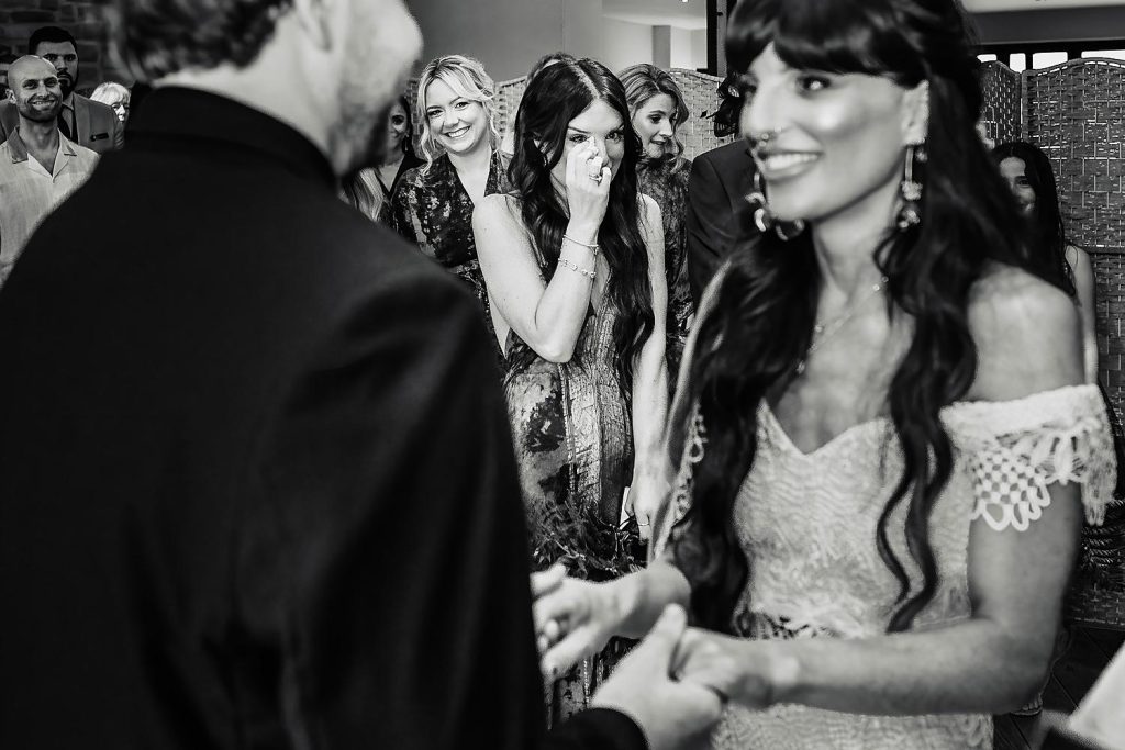 bridesmaid wipes tear whilst newlyweds exchange vows