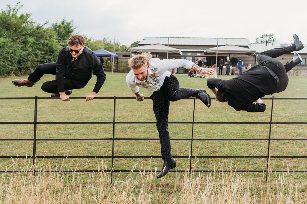 Groom and guests jump over a fence